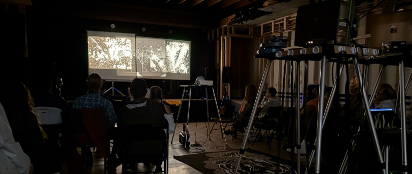 students gather for a film showing on a projector screen.