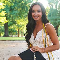 Erica DeVito on the Horseshoe with her cap cords and gown