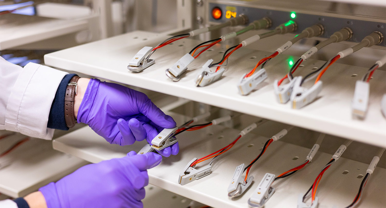Two gloved hands working with batteries
