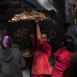 A man carries a tray of freshly baked bread outside a bread factory