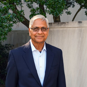 man stands in front of a building with greenery in the background