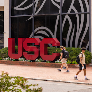 students walking past garnet USC sign