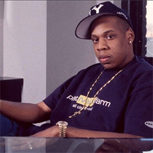 An African American adult male in black t-shirt and ballcap looks into the camera